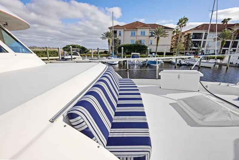 Slide: The Image of 1987 Hatteras 68 Cockpit Motor Yacht with striped seating, docked near waterfront homes. - 9