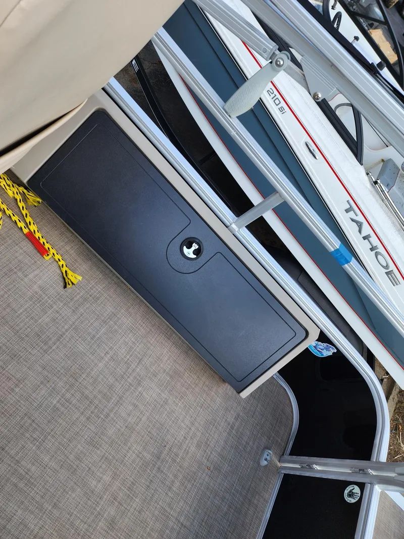 Slide: The Image of 2023 Sun Tracker SF24 boat interior with storage compartment and Tahoe branding. - 12