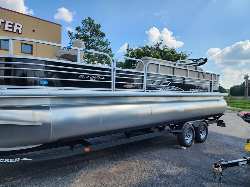 Slide: The Image of 2023 Sun Tracker SF24 pontoon boat on trailer, parked outdoors. - 14