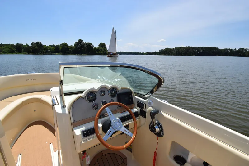 Slide: The Image of 2017 Chris-Craft Launch 25 boat interior with steering wheel, on a serene lake. - 15