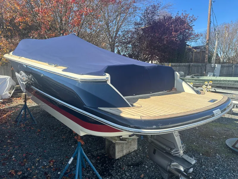 Slide: The Image of 2017 Chris-Craft Launch 25 boat with blue cover, parked on gravel. - 23