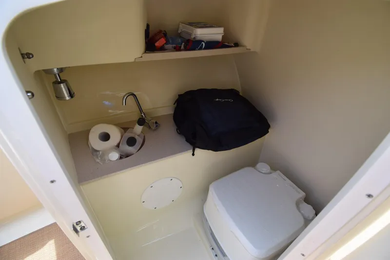 Slide: The Image of 2017 Chris-Craft Launch 25 interior with sink, toilet, and storage shelf. - 25