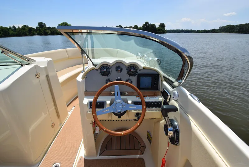 Slide: The Image of 2017 Chris-Craft Launch 25 boat interior with steering wheel and dashboard on a calm lake. - 6