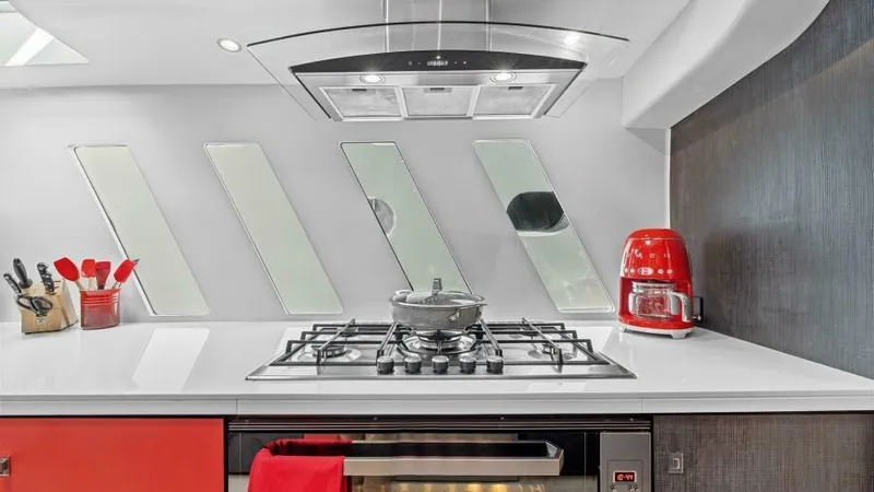 Slide: The Image of Modern yacht kitchen with sleek stove, red accents, and unique window design on Mystique Yachts Silhouette 800. - 30