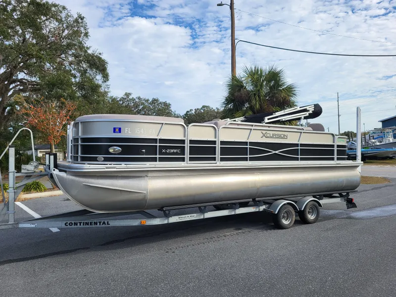 Slide: The Image of 2013 Xcursion X23RFC pontoon boat on trailer, parked outdoors. - 2
