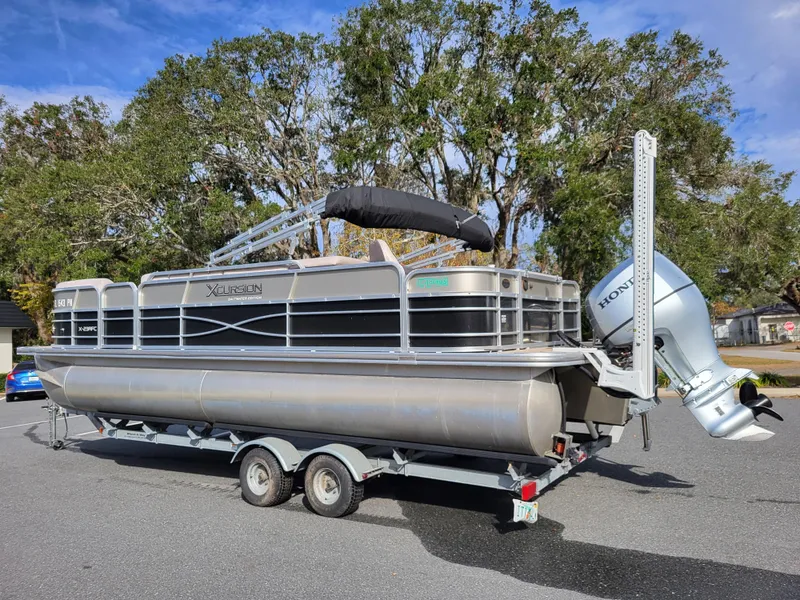 Slide: The Image of 2013 Xcursion X23RFC pontoon boat on trailer, parked outdoors. - 3