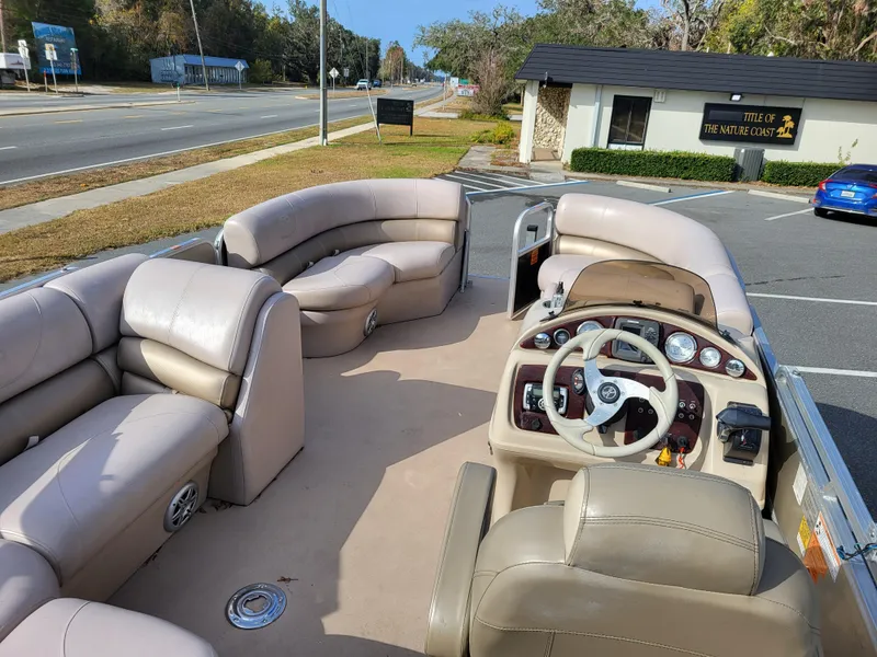 Slide: The Image of 2013 Xcursion X23RFC pontoon boat interior with beige seating and steering console. - 8
