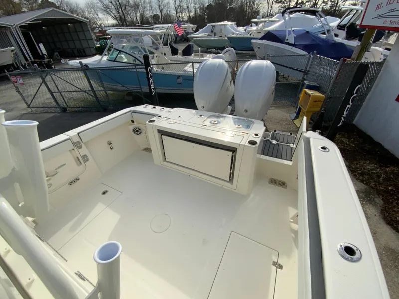 Slide: The Image of 2025 Cobia 285 Open Center Console boat in marina, showcasing spacious deck and dual engines. - 13