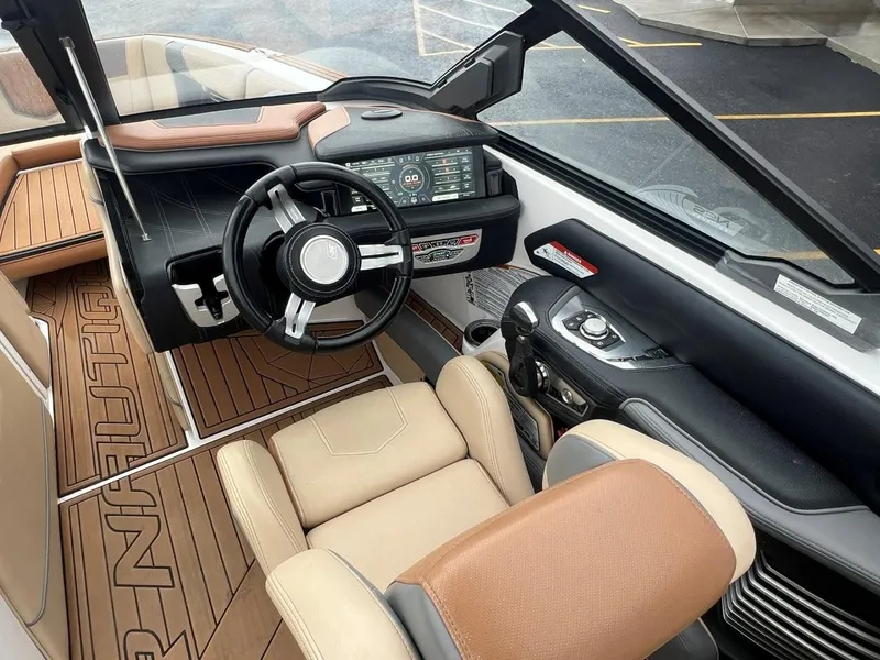 Slide: The Image of 2019 Nautique G25 boat interior with steering wheel, dashboard, and beige seating. - 15