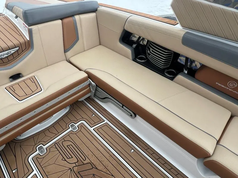 Slide: The Image of 2019 Nautique G25 boat interior with tan and brown seating, stylish flooring, and cup holders. - 17