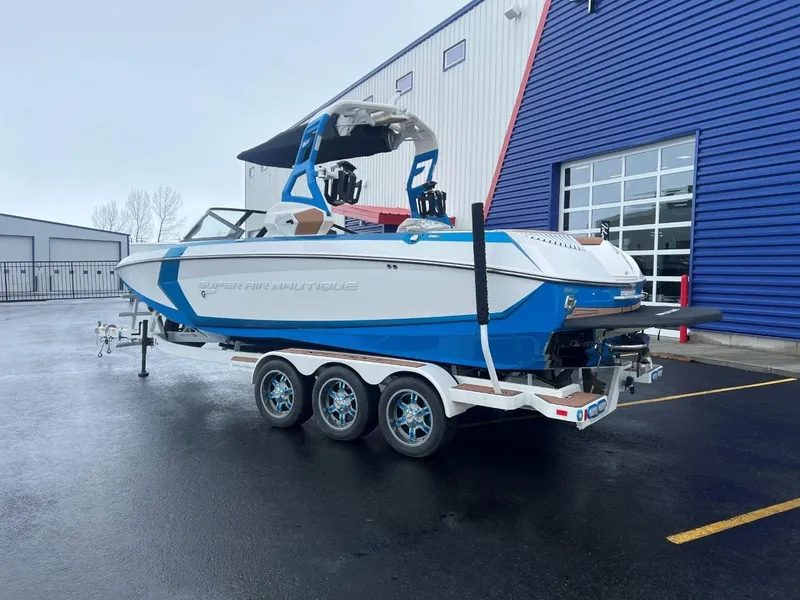 Slide: The Image of 2019 Nautique G25 boat on trailer, parked outside a blue building. - 4
