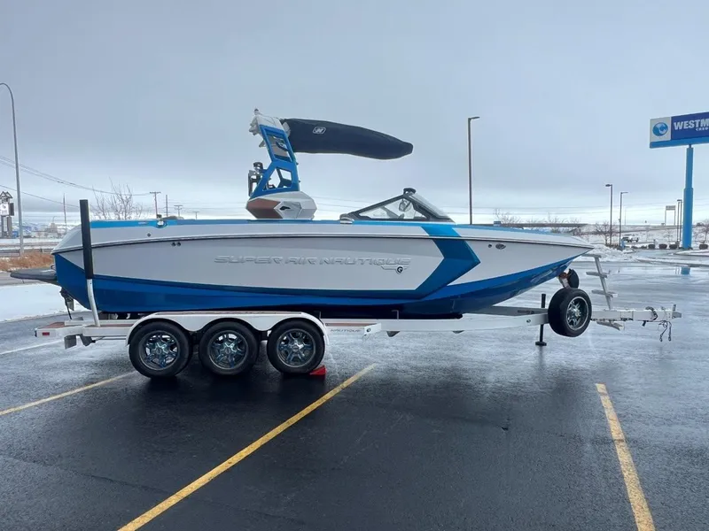 Slide: The Image of 2019 Nautique G25 boat on trailer, blue and white design, parked in lot. - 8