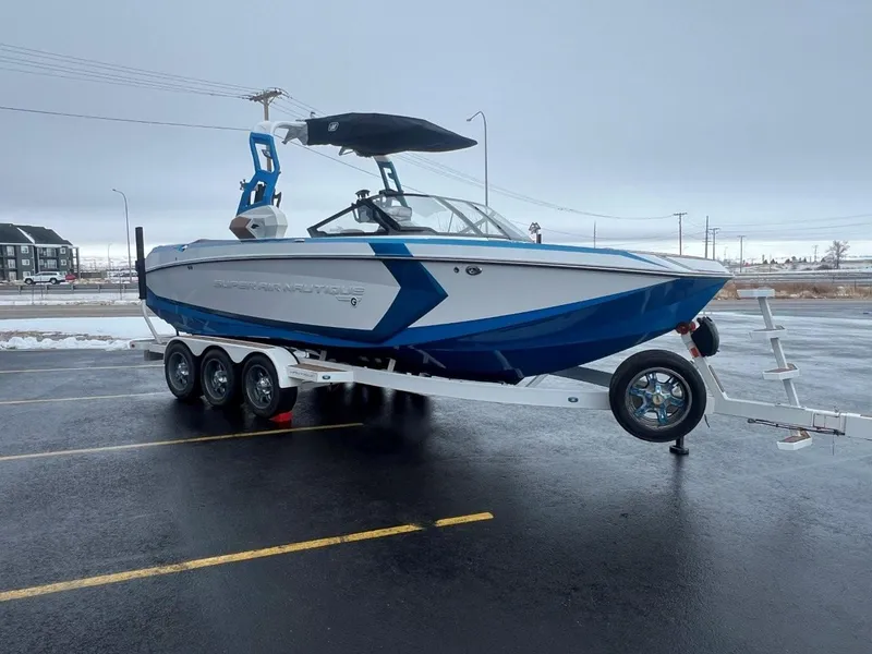 Slide: The Image of 2019 Nautique G25 boat on trailer, blue and white design, parked in lot. - 9