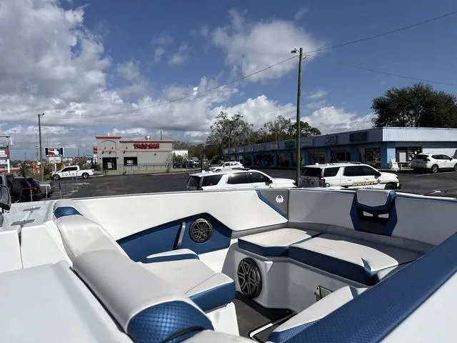 Slide: The Image of 2024 Scarab SBI285 boat interior with blue and white seating, parked in a lot. - 12
