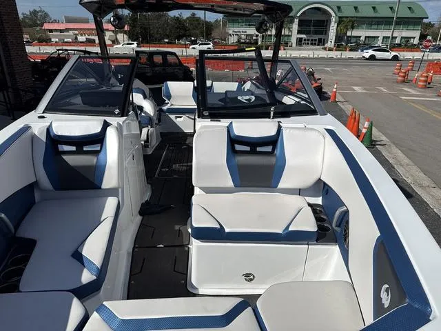 Slide: The Image of 2024 Scarab SBI285 boat interior with white and blue seating, parked near a building. - 16