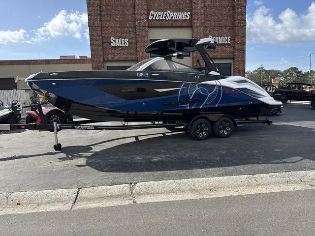 Slide: The Image of 2024 Scarab SBI285 boat on trailer outside CycleSprings dealership, sunny day. - 2