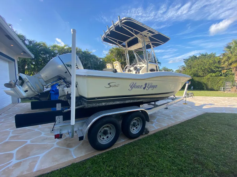 Slide: The Image of 2005 Scout 210 Sportfish boat on trailer, parked outdoors under blue sky. - 11