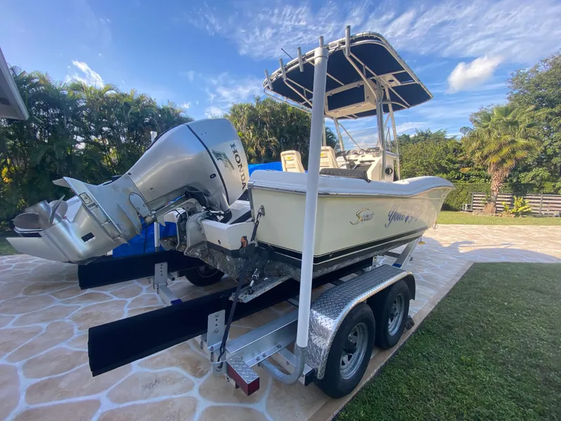 Slide: The Image of 2005 Scout 210 Sportfish boat on trailer with outboard motor, parked outdoors. - 12