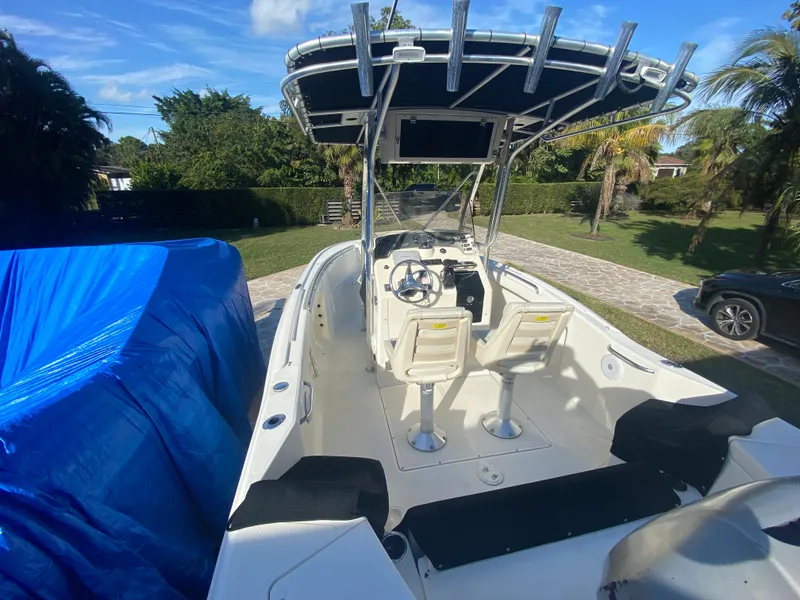 Slide: The Image of 2005 Scout 210 Sportfish boat with T-top, parked outdoors, blue tarp nearby. - 14