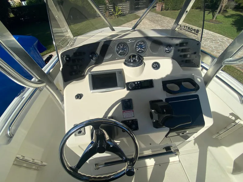 Slide: The Image of 2005 Scout 210 Sportfish boat dashboard with steering wheel and navigation controls. - 21