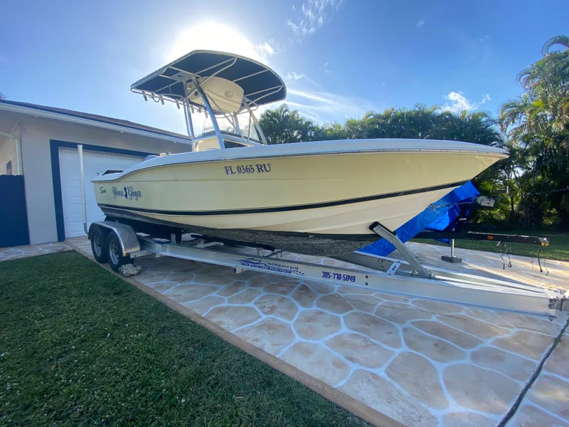 Slide: The Image of 2005 Scout 210 Sportfish boat on trailer, parked in driveway under clear sky. - 9
