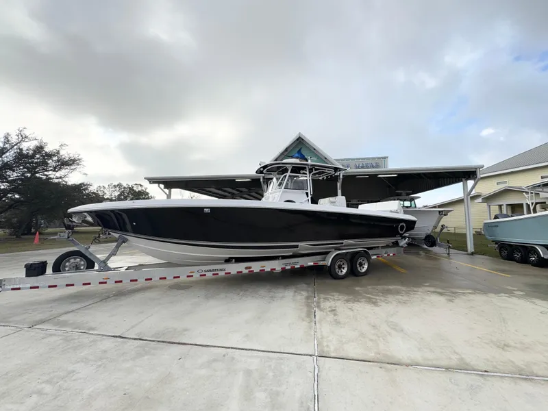 The Image of 2018 Fountain 34 CC boat on trailer, parked outdoors under cloudy sky. - 1