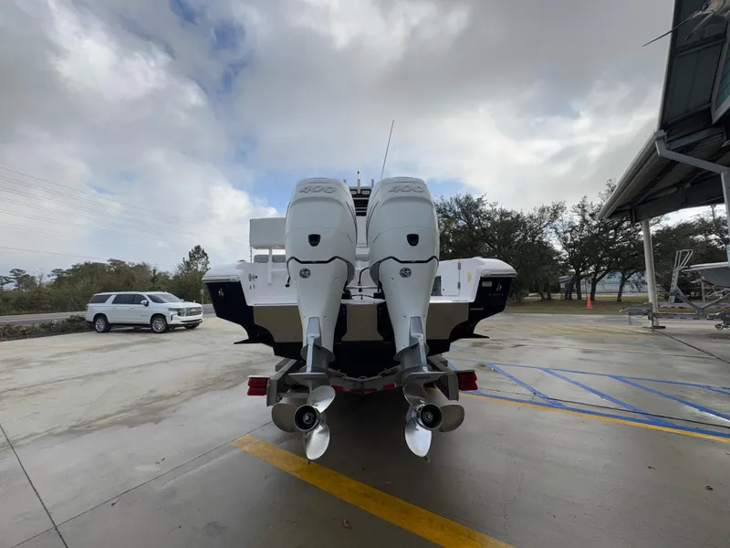 Slide: The Image of 2018 Fountain 34 CC boat with dual outboard motors in a parking area. - 17