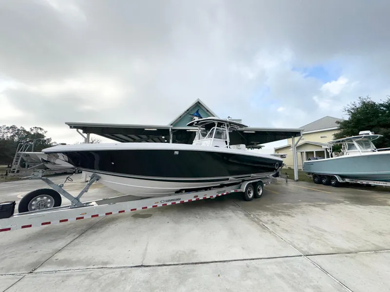 Slide: The Image of 2018 Fountain 34 CC boat on trailer in driveway, overcast sky. - 3