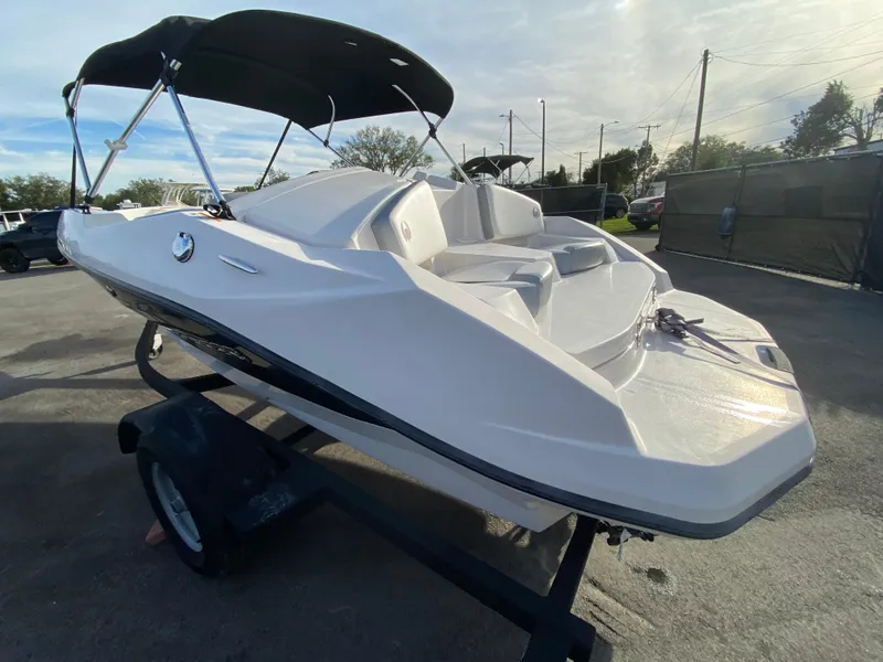 Slide: The Image of 2018 Scarab 165 G boat with canopy on trailer, parked outdoors. - 2