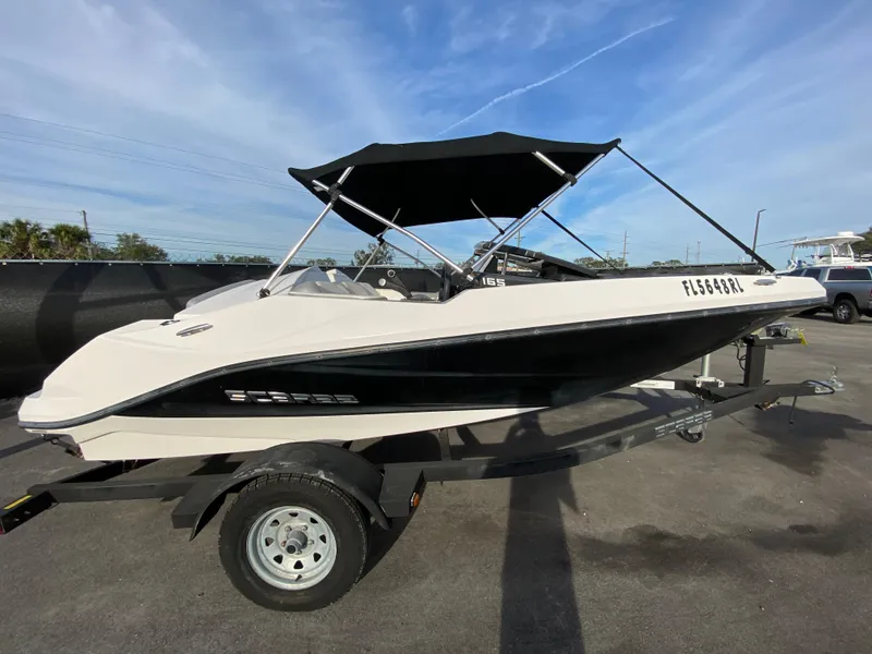 Slide: The Image of 2018 Scarab 165 G boat with black canopy on trailer, parked outdoors. - 5