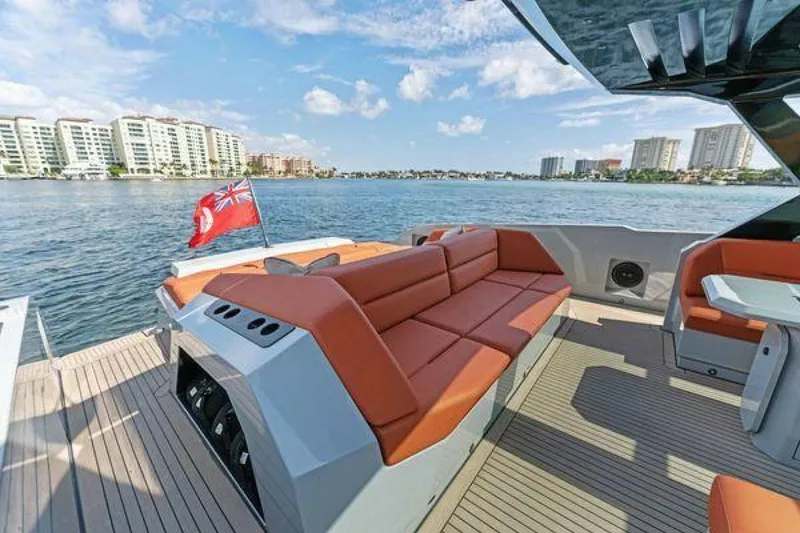 Slide: The Image of Luxurious 2021 Vanquish VQ58 yacht with spacious deck and seating, cruising near waterfront buildings. - 18
