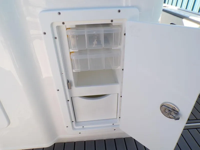 Slide: The Image of Tidewater 2700 CB 2025 boat storage compartment with open door and organized shelves. - 31