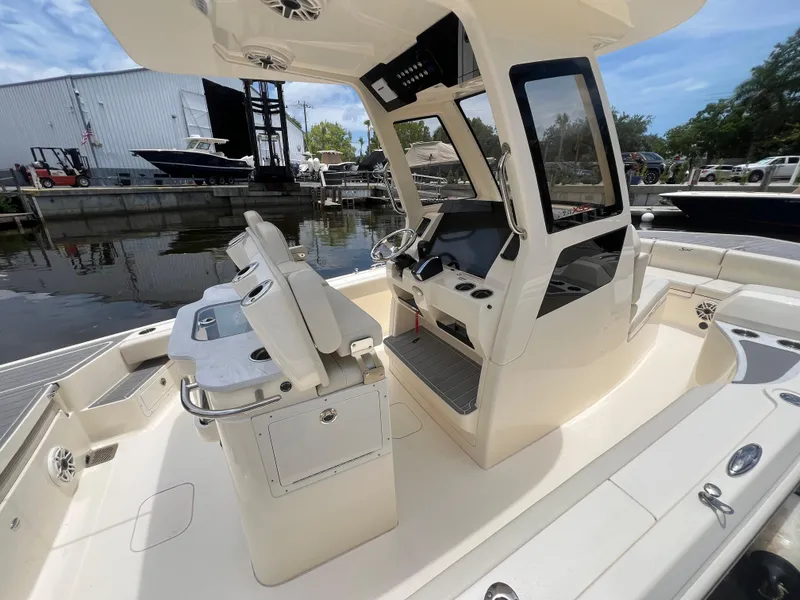 Slide: The Image of 2025 Scout 281 XSS boat interior with modern helm and seating, docked near other vessels. - 15