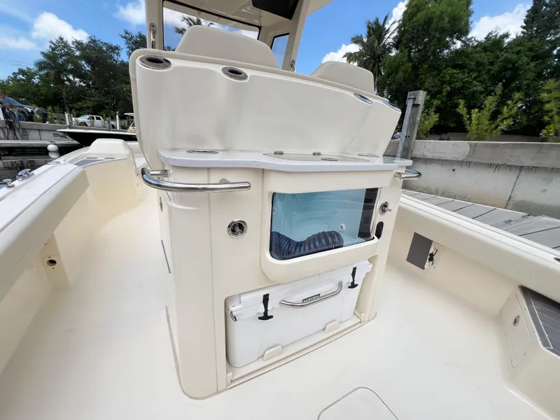 Slide: The Image of 2025 Scout 281 XSS boat interior with seating and storage, docked near lush greenery. - 16