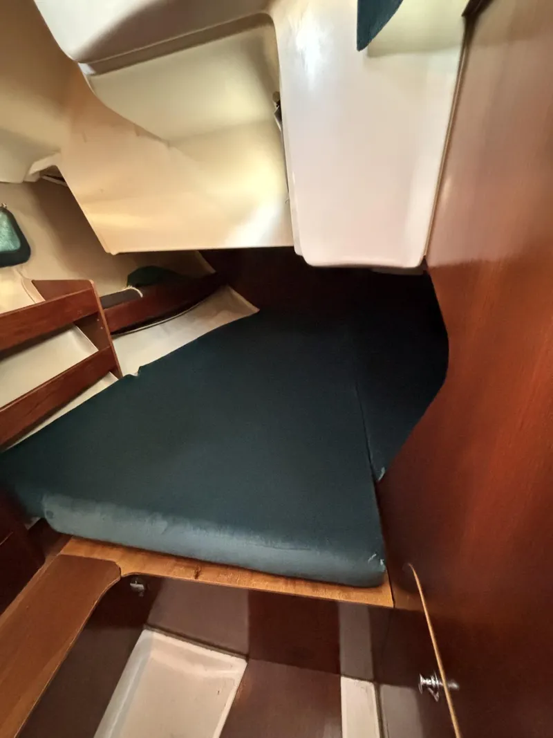 Slide: The Image of 1997 Beneteau Oceanis 351 cabin interior with dark cushions and wooden accents. - 14