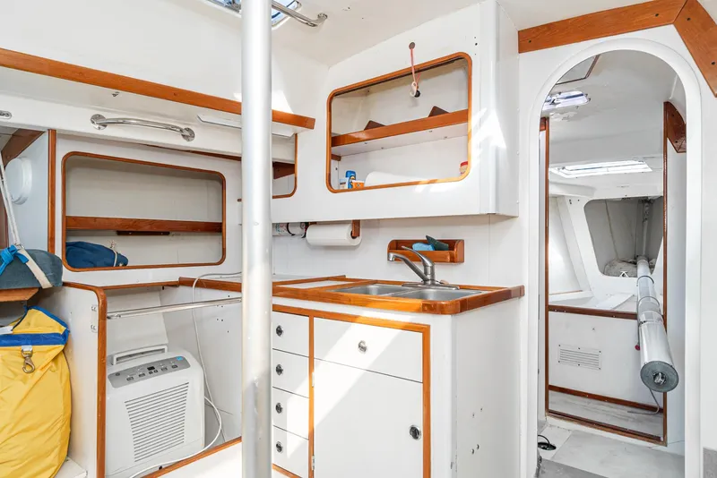 Slide: The Image of Interior of a 1992 Tripp 47 sailboat with wooden accents and compact kitchen area. - 38
