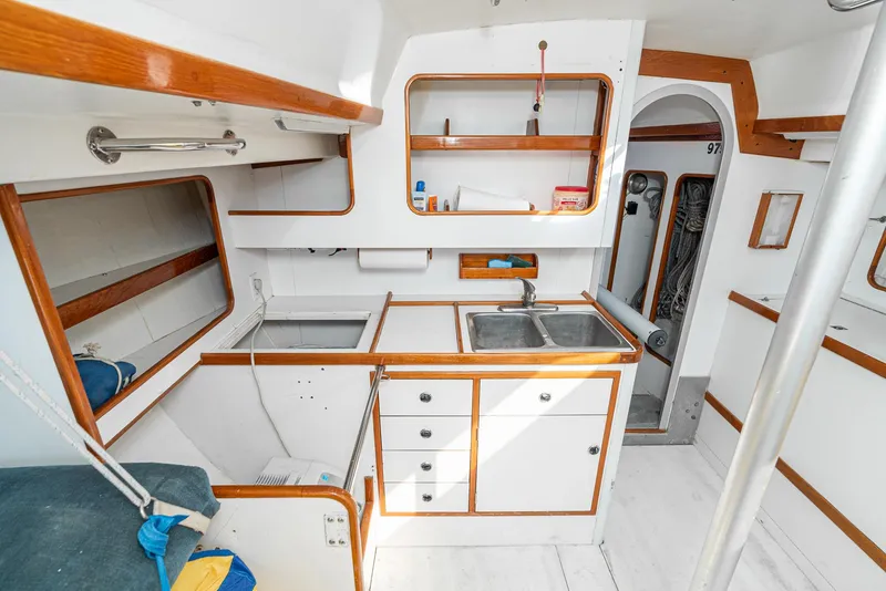 Slide: The Image of Interior of 1992 Tripp 47 sailboat, featuring a compact kitchen with wooden accents. - 39
