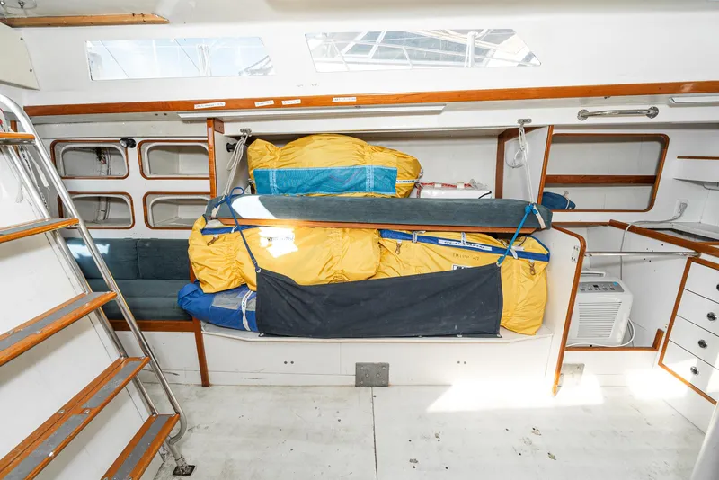 Slide: The Image of Interior of 1992 Tripp 47 sailboat with stored sails and wooden accents. - 47