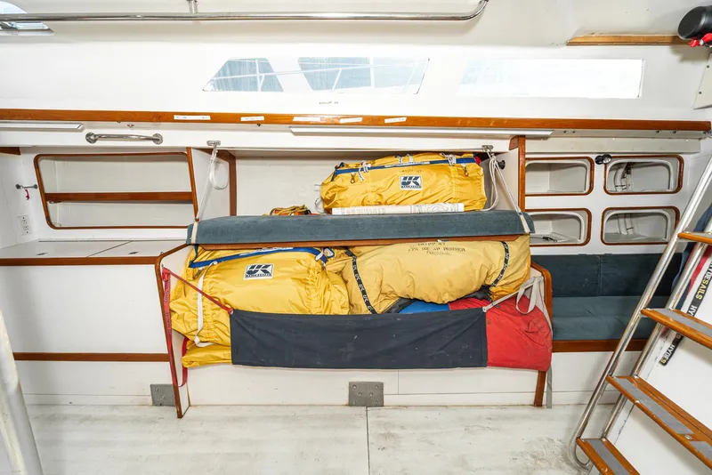 Slide: The Image of Interior of a 1992 Tripp 47 sailboat with stored yellow sails and wooden accents. - 49