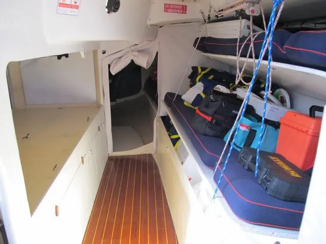 Slide: The Image of Interior of 1985 Santa Cruz 70 sailboat with wooden flooring and storage bunks. - 19