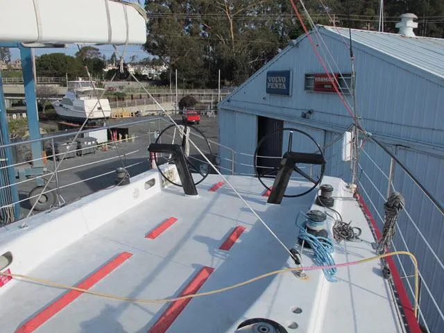 Slide: The Image of 1985 Santa Cruz 70 sailboat deck with dual steering wheels at a marina. - 32