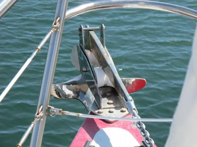 Slide: The Image of Anchor on 1985 Santa Cruz 70 sailboat, secured with chain over calm water. - 47