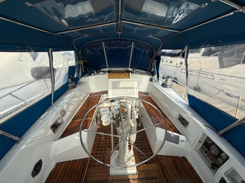 Slide: The Image of 1986 Beneteau Idylle 15.50 yacht cockpit with wooden flooring and blue canopy. - 18