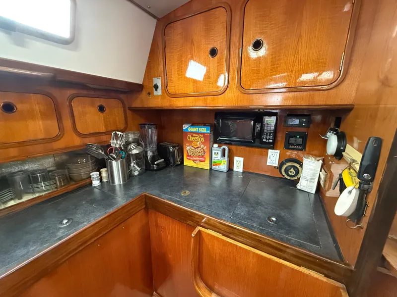 Slide: The Image of 1986 Beneteau Idylle 15.50 yacht kitchen with wooden cabinets and modern appliances. - 32