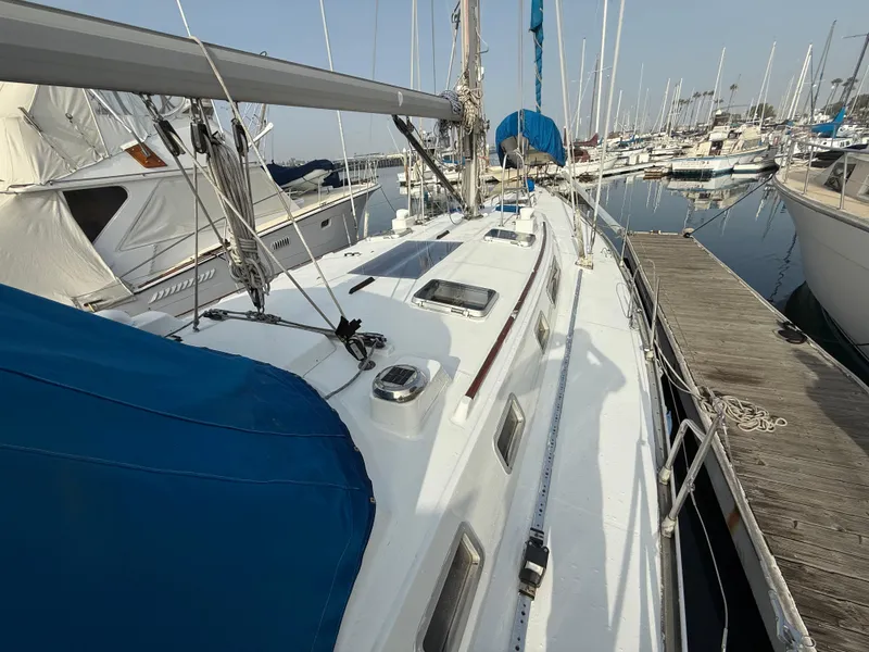 Slide: The Image of 1986 Beneteau Idylle 15.50 sailboat docked at marina, featuring blue covers and sleek design. - 8
