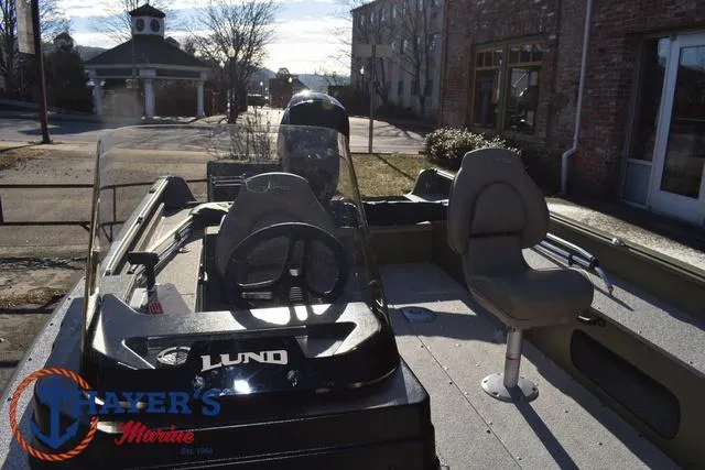 Slide: The Image of 2025 Lund 1875 Alaskan SS boat with steering console and seating, parked outdoors. - 17