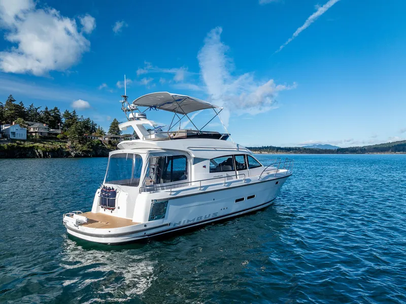 Slide: The Image of 2024 Nimbus 405 Flybridge yacht cruising on a serene blue lake under a clear sky. - 27