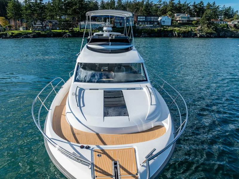 Slide: The Image of 2024 Nimbus 405 Flybridge yacht on serene water, surrounded by lush greenery. - 30