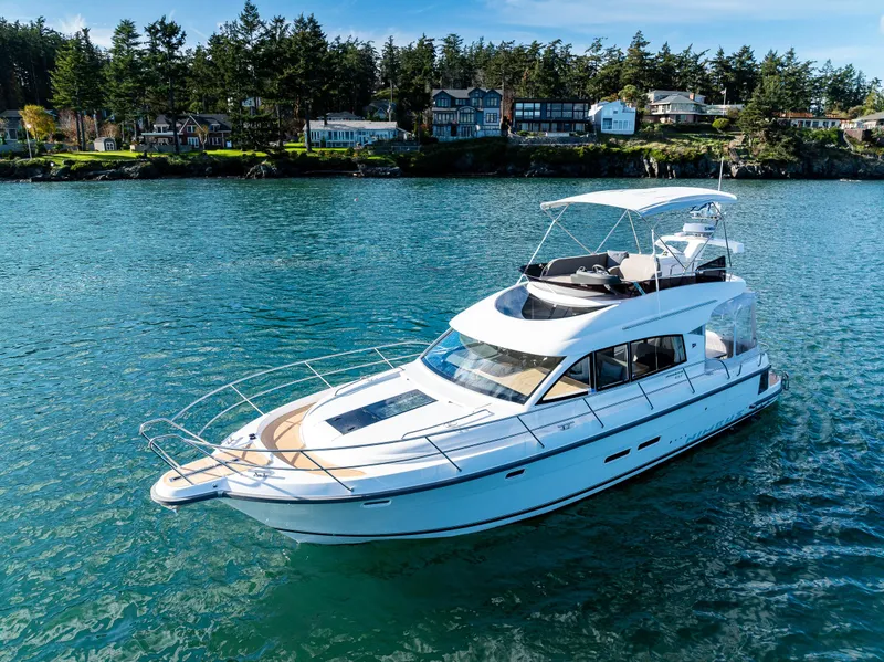 Slide: The Image of 2024 Nimbus 405 Flybridge yacht cruising on a serene lake with scenic shoreline. - 32