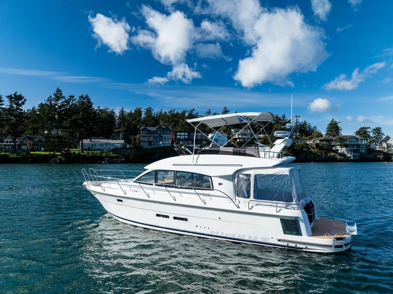 Slide: The Image of 2024 Nimbus 405 Flybridge yacht cruising on a serene lake under a clear blue sky. - 35